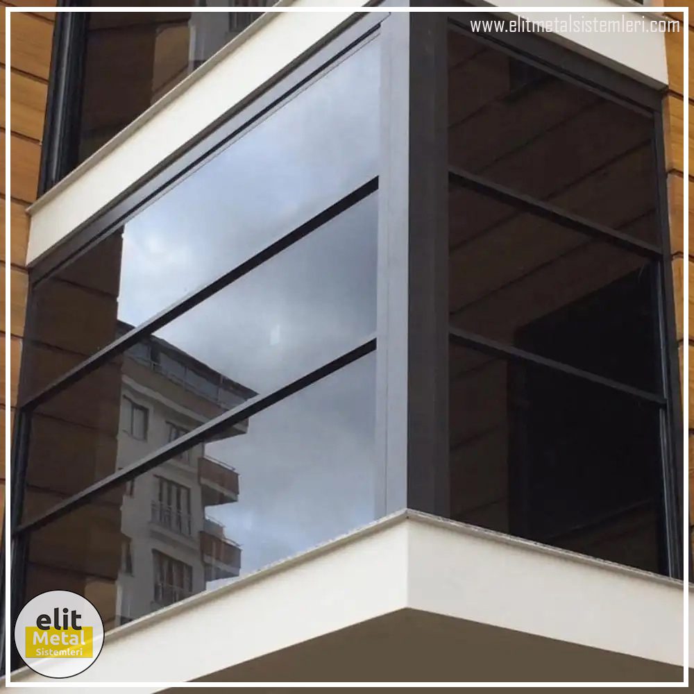 Elit Metal Sistemleri siyah alüminyum profilli, yatay bölmeli ve füme camlı köşe balkon kapama uygulaması.